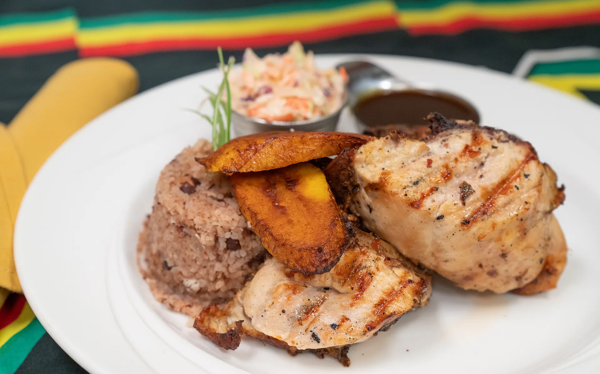 Grilled jerk chicken with rice and peas, fried plantain and coleslaw